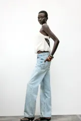 Top corto blanco confeccionado con lino, de tirantes finos, escote pico y espalda abierta con tira elástica horizontal. Tiene bajo abullonado con elástico interior.