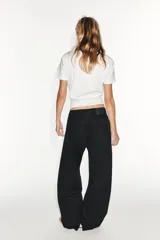 Jeans de tiro medio estilo balloon en color negro, con diseño de cinco bolsillos, trabillas para cinturón y cierre frontal con cremallera y botón metálico.