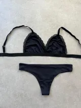 Conjunto de bikini negro con corpiño triangular con detalle de encaje y bombacha less.