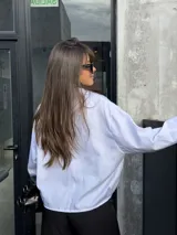 Camisa blanca de diseño oversize, con mangas largas, bolsillos frontales con solapa y cierre de botones.