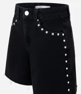 Short midi de jean azul con tiro medio, bolsillos frontales y traseros, trabillas para cinturón y detalle de tachas metálicas aplicadas en los laterales y bolsillos. El diseño se completa con un dobladillo deshilachado.