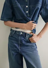 Jeans de denim azul de tiro medio y diseño wide leg largo, con cinco bolsillos, trabillas para cinto y cierre de botón y cremallera.