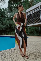Falda midi de corte cruzado con diseño tipo pareo, presenta un nudo decorativo en la parte delantera y cierre de cremallera oculta en la espalda. El tejido cuenta con un estampado geométrico abstracto en tonos bordó, negro, amarillo y crema.
