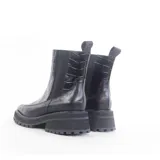 Botas de cuero negro con caña corta, elástico lateral, suela track y detalle de textura croco en el empeine.