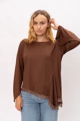 Blusa de tela elastizada color marrón, con corte asimétrico, mangas anchas y detalle de puntilla en el ruedo.