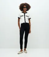 Pantalón skinny negro de cintura alta, confeccionado en sarga de algodón con elastano. Presenta bolsillos funcionales y detalle de botones dorados en los ruedos.