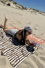 Pareo de playa con estampado de rayas horizontales blancas y marrones.