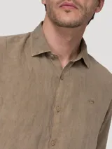 Camisa de manga larga de lino color tostado de la marca RKF, con cierre frontal de botones y cuello camisero clásico. Presenta un pequeño logo bordado en el pecho.