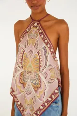 Top halter de viscosa con estampado tipo pañuelo en tonos rosados, bordó y beige con detalles florales y geométricos. Presenta corte en punta y tirantes finos para anudar al cuello.