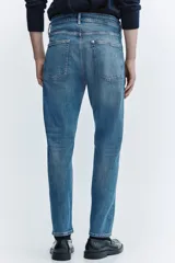 Pantalón jean de corte ajustado y tiro medio, en tono azul clásico con efecto deslavado.