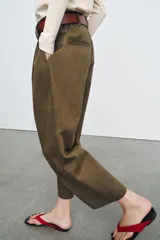 Pantalón cropped de tiro medio con diseño de pinzas en el delantero, bolsillos laterales y bolsillos de vivo en la parte trasera. Cuenta con trabillas en la cintura y cierre frontal con cremallera y botón.