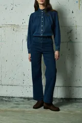 Pantalón de jean azul oscuro de corte recto y tiro alto, con costuras reforzadas y cierre frontal con botones.