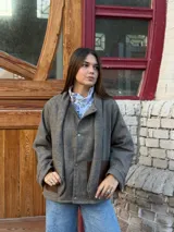 Blazer de lana en tono marrón con textura espigada, cuello con lazo integrado y bolsillos frontales de cuero en contraste.