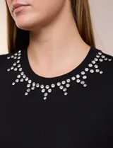 Remera blanca de calce recto y cuello redondo, confeccionada en suave jersey con detalle de aplicación de piedras brillantes a modo de gargantilla en el escote.