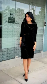 Vestido midi de terciopelo negro, con mangas largas, cuello redondo y detalle de encaje bordado en el lateral de la cintura.