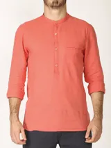 Camisa de lino color rosado, con cuello mao y cierre frontal parcial con botones. Presenta mangas largas y un bolsillo pequeño en el pecho.