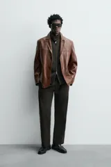 Blazer de corte relajado confeccionada en piel napada, con cuello de solapas de muesca, manga larga y cierre frontal de tres botones. Presenta bolsillos con solapa en la parte delantera.
