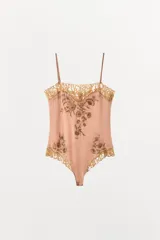 Body de satén color rosado con escote recto, tirantes finos ajustables y detalles de encaje en contraste. Presenta bordados florales con abalorios en el frente y cierre inferior con botones a presión.