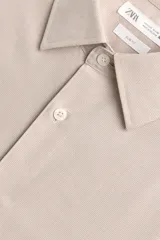 Camisa slim fit color beige, confeccionada en tejido de algodón, con cuello italiano y manga larga con puño de botón. Cierre frontal de botonadura.