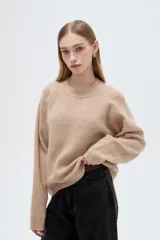 Sweater holgado de punto color beige con cuello redondo a la base y mangas largas raglán.