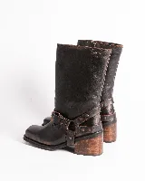 Bota de cuero negra con caña media, punta cuadrada, taco bloque y arnés con hebillas y tachas plateadas.