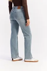 Jean de corte recto y tiro medio, confeccionado en denim de tono azul claro con acabado lavado. Presenta cierre frontal con botón y cremallera, además de bolsillos laterales y traseros.