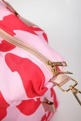 Bolso tipo duffel con estampado animal print en tonos crema y negro. Cuenta con correas de mano y correa ajustable para el hombro en color negro, cierre principal superior y bolsillo frontal con cierre.