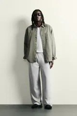 Pantalón jogger de corte relajado y pernera ancha, confeccionado en tejido de algodón con interior perchado. Cuenta con cintura elástica ajustable mediante cordón interior, bolsillos laterales y un bolsillo trasero de plastrón.
