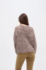 Sweater de tejido de punto con efecto jaspeado, corte holgado y cuello redondo. Presenta mangas largas con puños en contraste de color, uno en tono oscuro y otro en tono rojizo.
