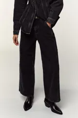Pantalón de jean negro con lavado gastado, corte culotte, tiro alto, bolsillos delanteros y traseros, y cierre frontal con cremallera y botón.