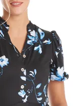 Vestido midi de seda fría con estampado floral en tonos azules sobre fondo negro. Presenta escote en V con cierre frontal de botones, mangas cortas con terminación fruncida, corte en la cintura con lazo de ajuste y falda plisada.
