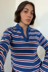 Camiseta polo de manga larga a rayas horizontales en tonos azul, blanco y bordó, con cuello tipo polo y escote en V profundo. Presenta pequeño bordado en el pecho.
