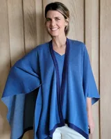 Ruana de tejido de punto en color crema con detalle de estrella grande en color verde lima en la espalda y bordes en tono arena.