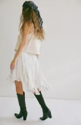 Pollera midi blanca de viscosa con volados irregulares en capas. Se ajusta a la cintura con un cinturón negro con hebilla metálica.