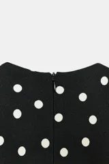 Vestido midi de lunares, color negro con lunares blancos, escote en V y mangas sisa con hombreras. Presenta frunces laterales en la cintura y cierre en la espalda con cremallera oculta.