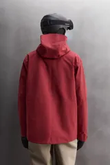 Cazadora deportiva de esquí con diseño bicolor en tonos negro y verde oliva. Presenta capucha amplia con visera, cierre frontal con cremallera termosellada, bolsillos frontales y en manga con cierres impermeables, y aberturas de ventilación en las axilas. Incluye faldón interior antinieve, puños ajustables y tecnología de rescate RECCO.