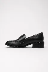 Mocasín clásico de cuero negro, con taco bajo y ancho de 4 cm. Combina laterales lisos con un panel frontal de acabado brillante y textura sutil, con una banda ancha sobre el empeine.