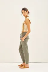 Pantalón tipo babucha de gabardina elastizada, color negro, con cintura elástica ajustable mediante cordón, puños en los tobillos, bolsillos diagonales frontales y bolsillos traseros con solapa y botón.