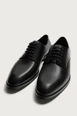Zapato de vestir tipo derby en color negro, con diseño de parte superior lisa, horma redonda y suela con ligero tacón.