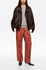 Pantalón de tiro medio y corte recto, con diseño estampado de manchas oscuras sobre base rojiza. Cuenta con cierre frontal de cremallera y corchete, bolsillos laterales y bolsillos traseros de vivo.