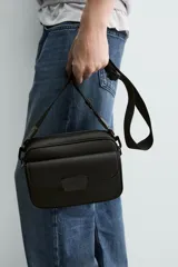Bandolera de diseño compacto con acabado texturizado, compartimento principal con cierre de cremallera, bolsillo frontal con cierre magnético y correa ajustable y extraíble.
