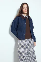 Campera de jean de calce relajado y corte cropped, con cuello y detalles en pana marrón. Presenta cierre frontal con botones metálicos y bolsillos con solapa en el pecho.