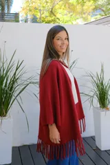 Saco abierto tipo capa en color bordó, confeccionado en tejido de punto suave, con mangas amplias y detalle de flecos en el ruedo.