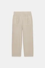 Pantalón de tiro medio color amarillo, con cintura elástica, bolsillos de plastrón en el delantero y pernera holgada que se estrecha hacia el tobillo. Cuenta con cierre frontal de cremallera y botón.