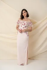 Vestido largo de tul bordado en color rosado, con flores bordadas en tonos fucsia y rosado en la parte superior, tajo lateral y mangas caídas.