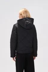 Campera acolchada de color negro con diseño de rombos, manga larga, capucha ajustable con cordones y cierre frontal con botones a presión.