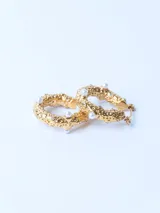 Par de aros dorados tipo argolla con textura y apliques de perlas.