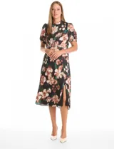 Vestido midi de satén con estampado floral sobre fondo negro. Presenta cuello a la base con frunce, mangas cortas abullonadas con terminación elástica, cintura definida y un tajo lateral pronunciado. Incluye forro interno y lazo posterior para ajustar el cuello.