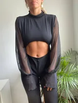 Mono largo negro con cuello alto, mangas largas de tul y abertura en el abdomen.