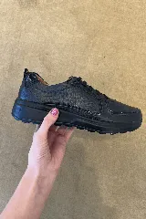 Champión urbano de cuero negro con textura combinada, suela de poliuretano liviana y flexible, y cierre con cordones al tono.